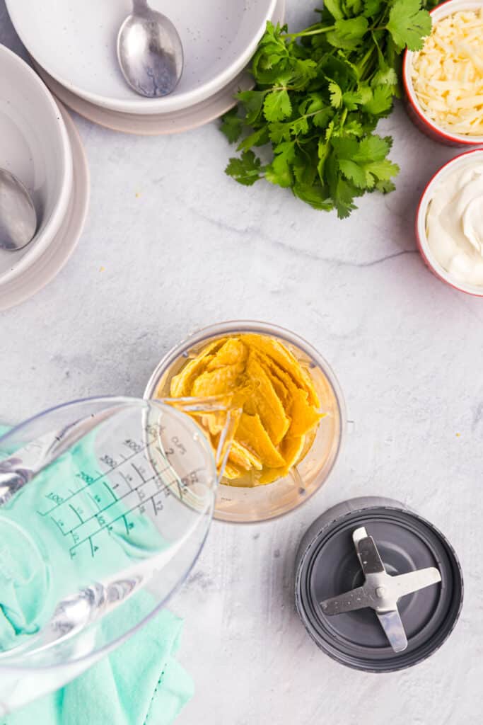 water pouring into a bowl of shredded tortillas.