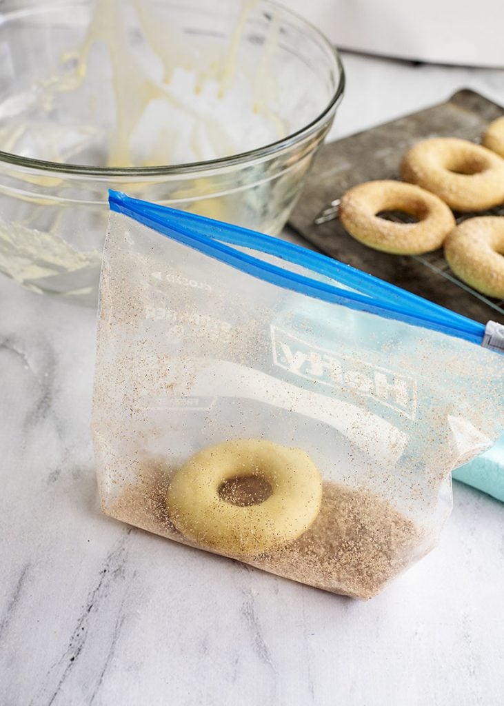 shaking a donut in a freezer bag with cinnamon and sugar