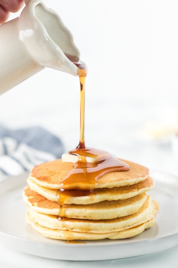syrup pouring over a stack of pancakes.