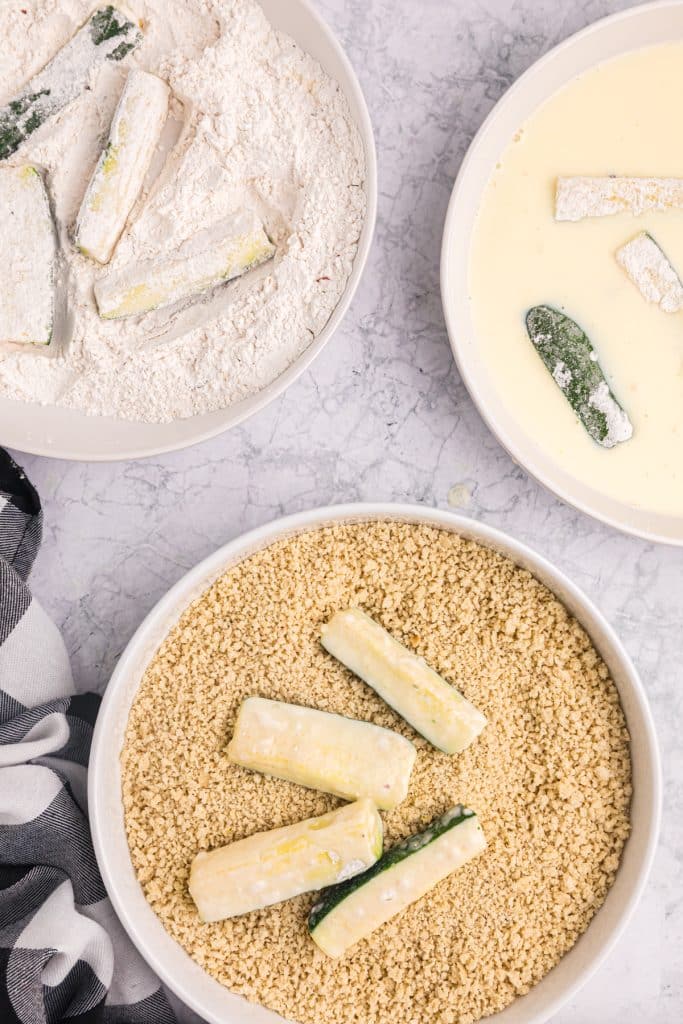 zucchini sticks laying in panko breadcrumb mixture.