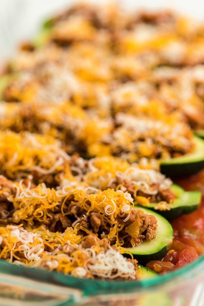 zucchini boats with shredded cheese in pan reay for baking