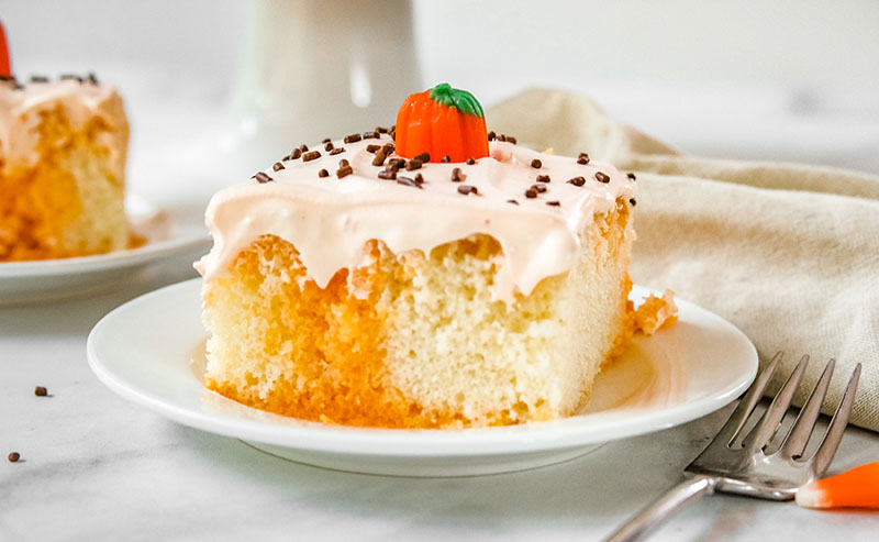 slice of orange poke cake with pumpkin on top