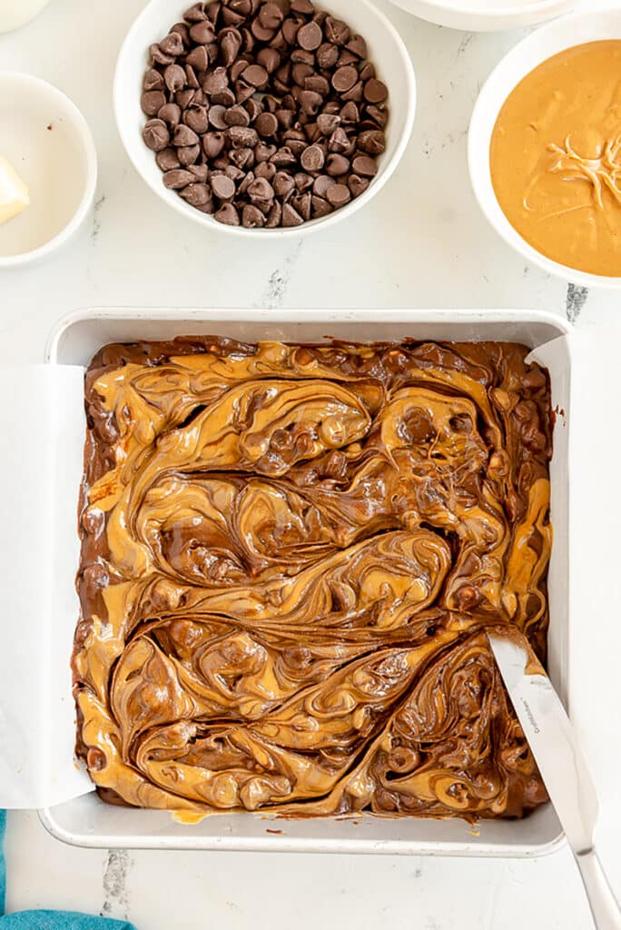 a knife swirling peanut butter into brownie batter.