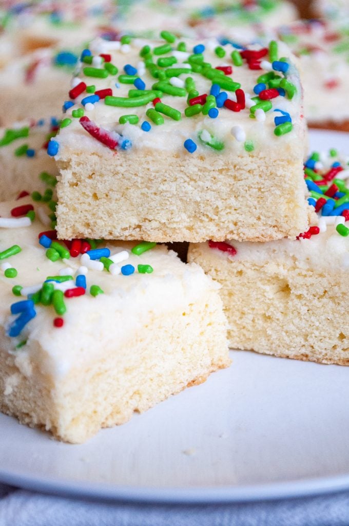 plate full of stacked frosted sugar cookie bars