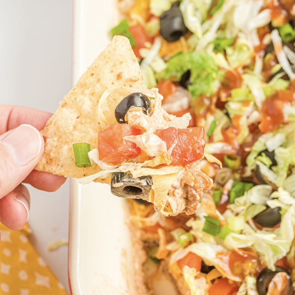 dipping tortilla chip into an easy taco dip recipe