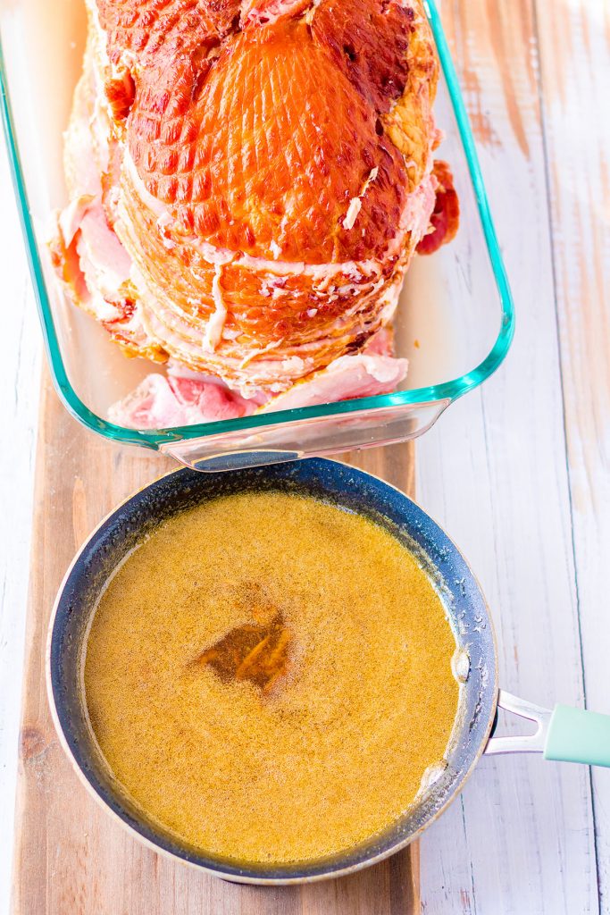 overhead shot of spiral ham in dish and glaze in a pot