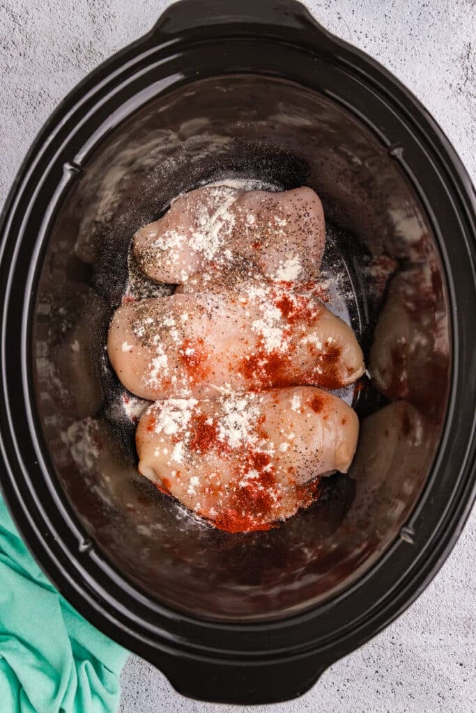 overhead shot of seasoned chicken breasts in a crockpot.