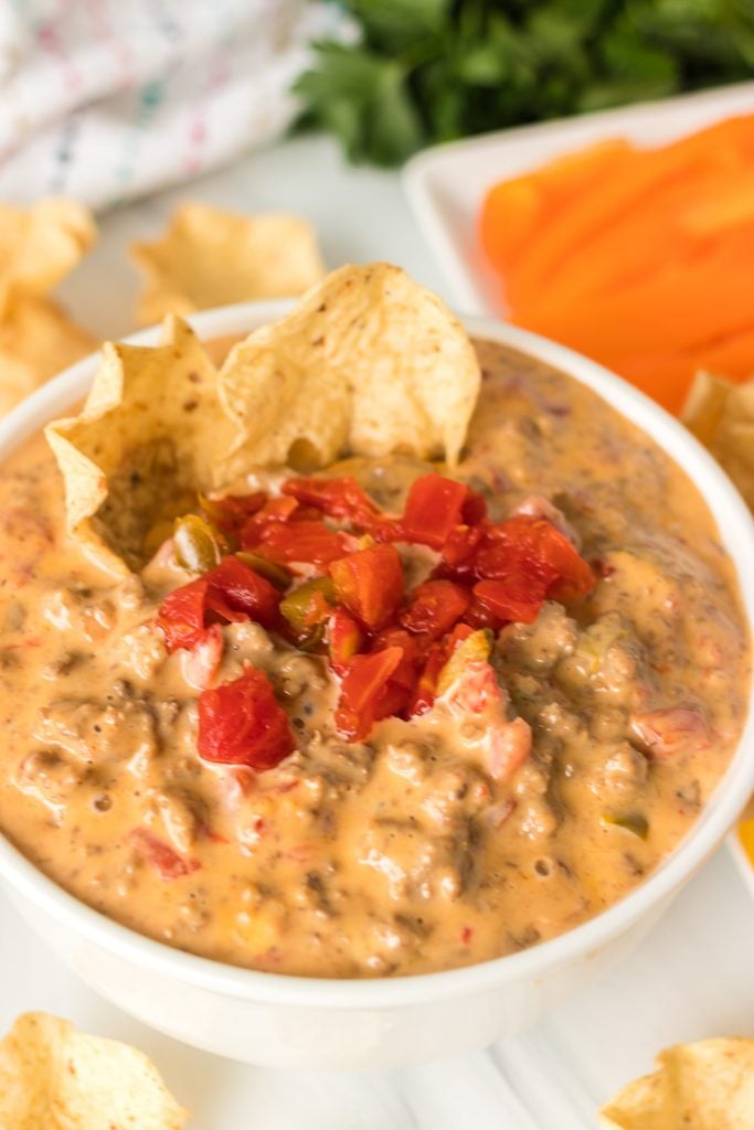 white bowl of beefy rotel dip with chips dipped in
