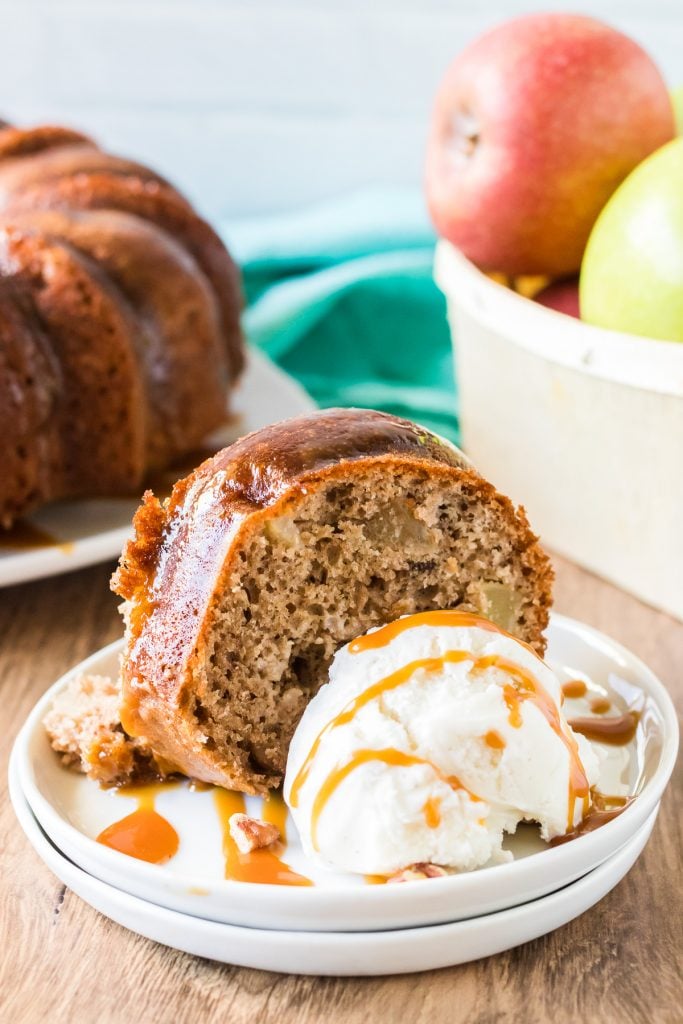 slice of apple bundt cake with vanilla ice cream drizzled with caramel on white plates