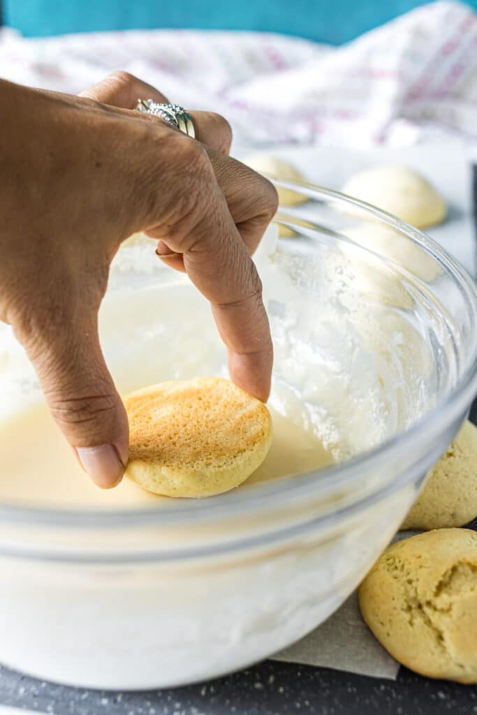 hand dipping a sugar cookie in icing.