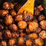 wooden spoon scooping teriyaki meatballs from slow cooker