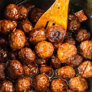 wooden spoon scooping teriyaki meatballs from slow cooker