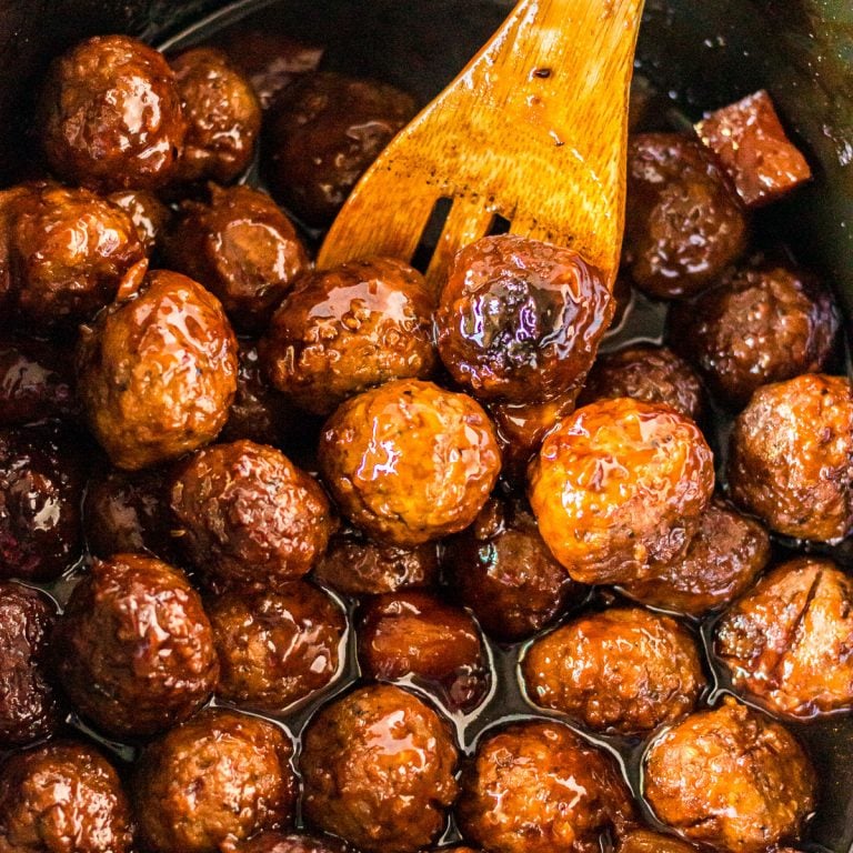 wooden spoon scooping teriyaki meatballs from slow cooker