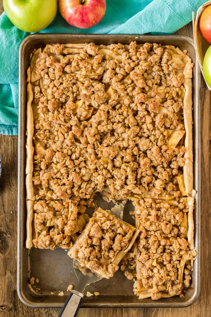 overhead shot of a slice of apple slab pie being removed from a baking sheet