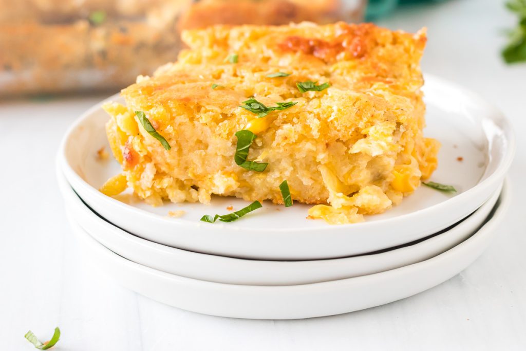 portion of corn casserole on a stack of white plates