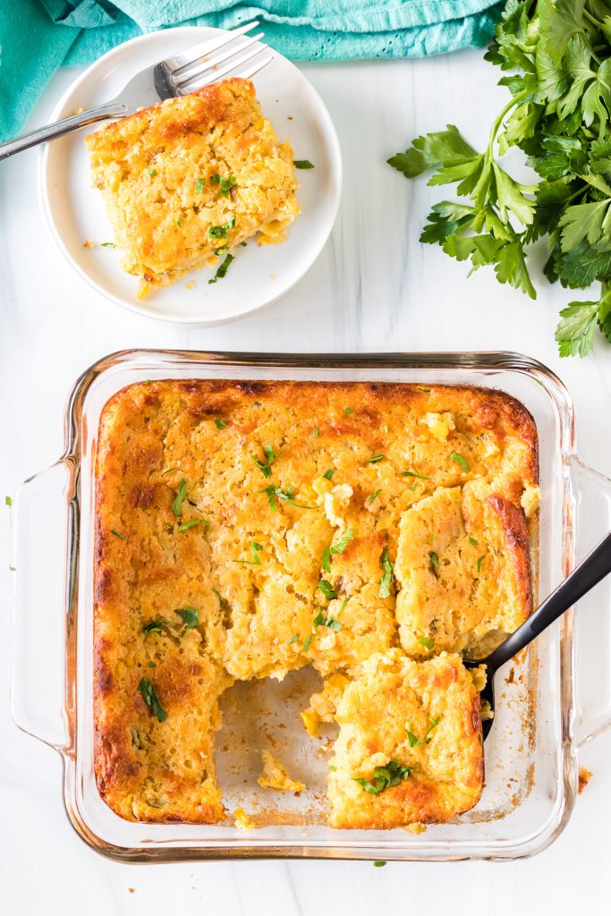 overhead shot of corn casserole with a black spoon in a baking dish