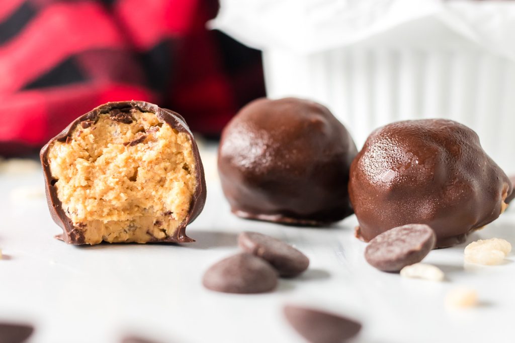 closeup of a chocolate covered pb rice krispie ball with a bite taken out of it