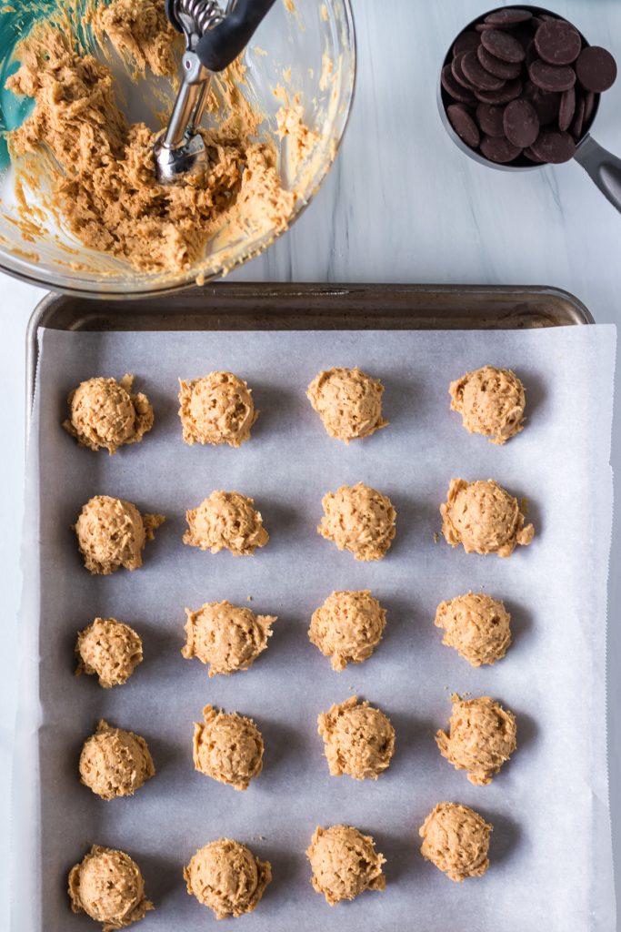 overhead shot of peanut butter rice krispie balls being scooped onto a baking sheet