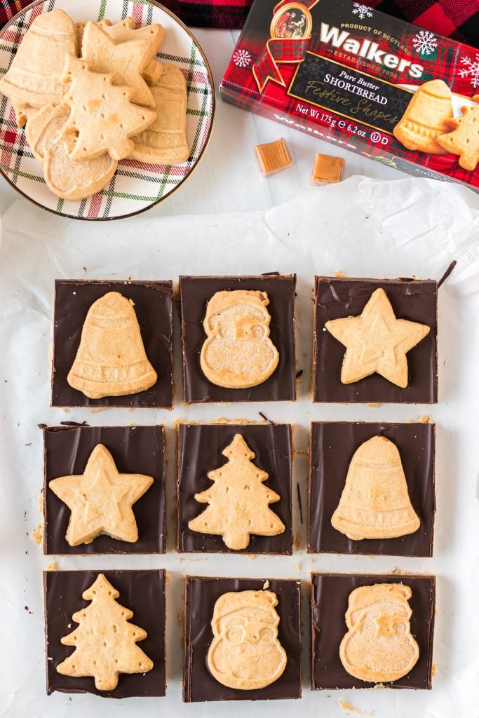 overhead shot of sliced millionaire bars topped with christmas shaped cookies
