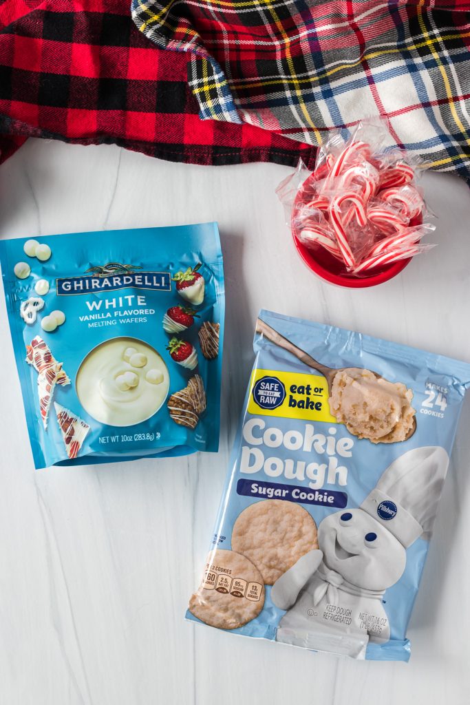 overhead shot of sugar cookies, white chocolate candy melts, and candy canes laid out to make cookies