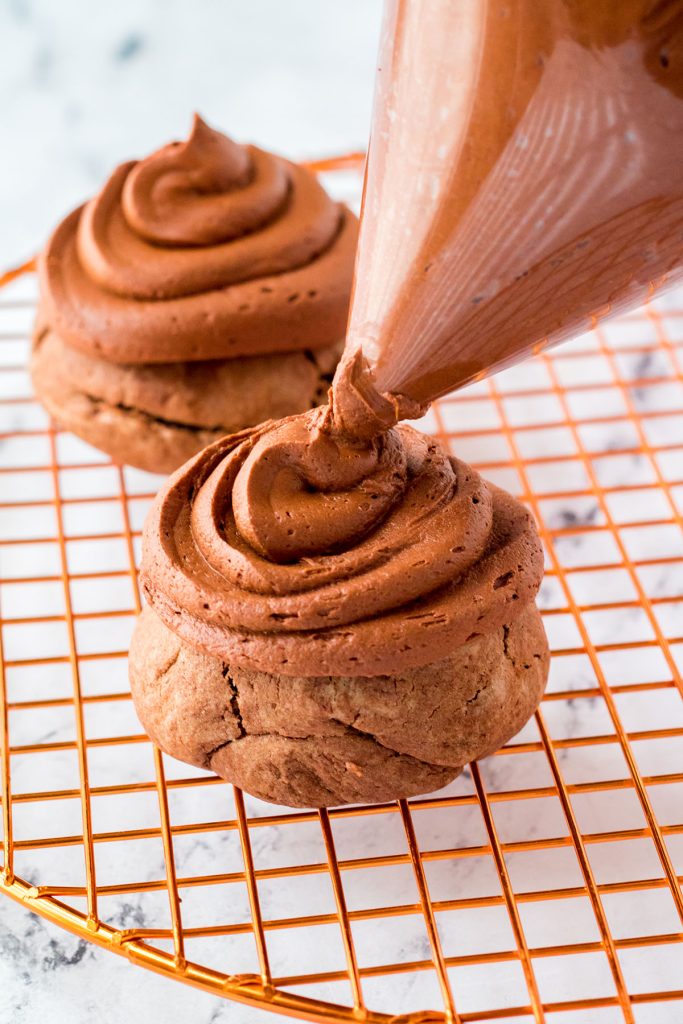 chocolate buttercream being piped onto a chocolate cookie.