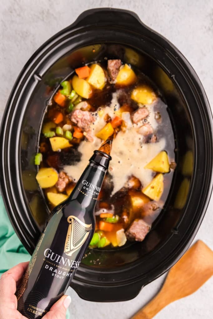 guinness beef pouring into a crockpot of stew.