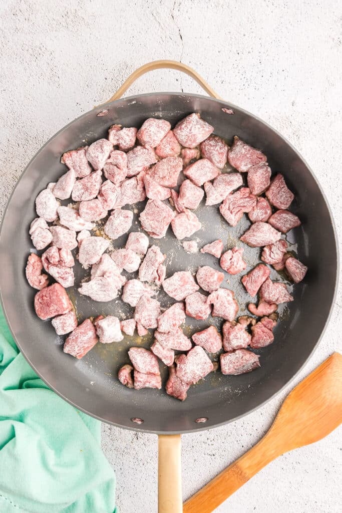 floured stew beef pieces in a skillet.
