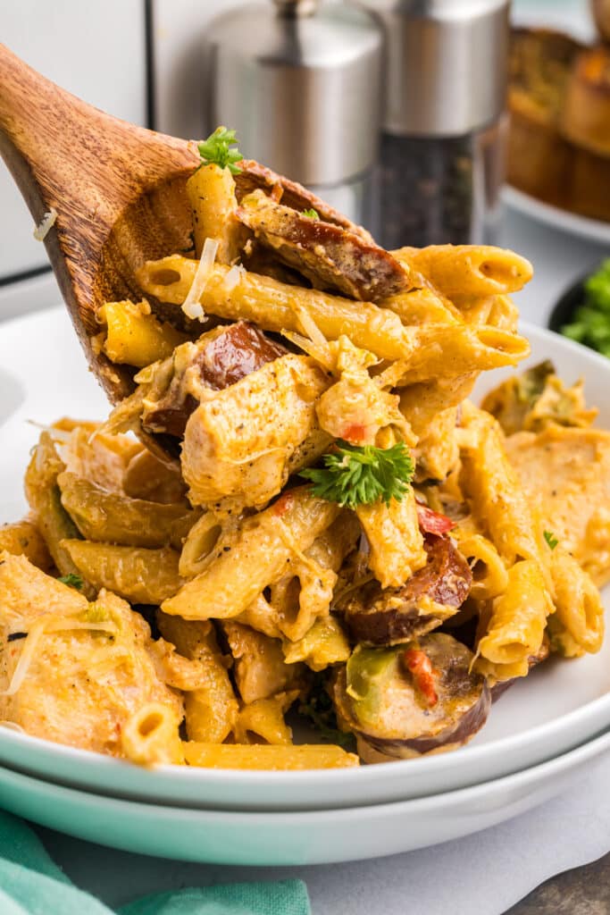 cajun pasta being spooned onto a white plate.