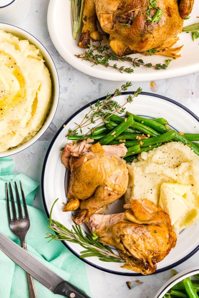 overhead shot of cornish hens plated with mashed potatoes & green beans.
