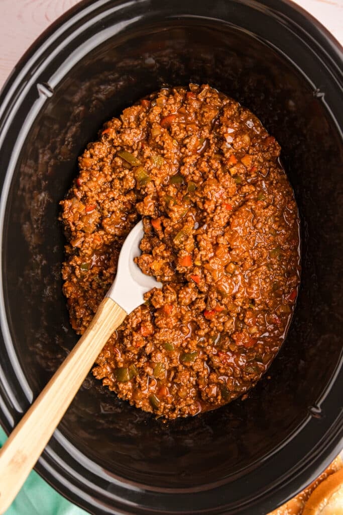 spoon lifting sloppy joe mixture from a crockpot.