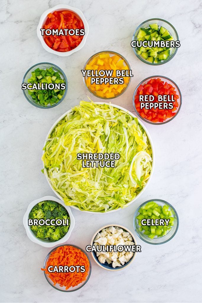 overhead shot of bowls holding  diced vegetables prepped to make a salad.