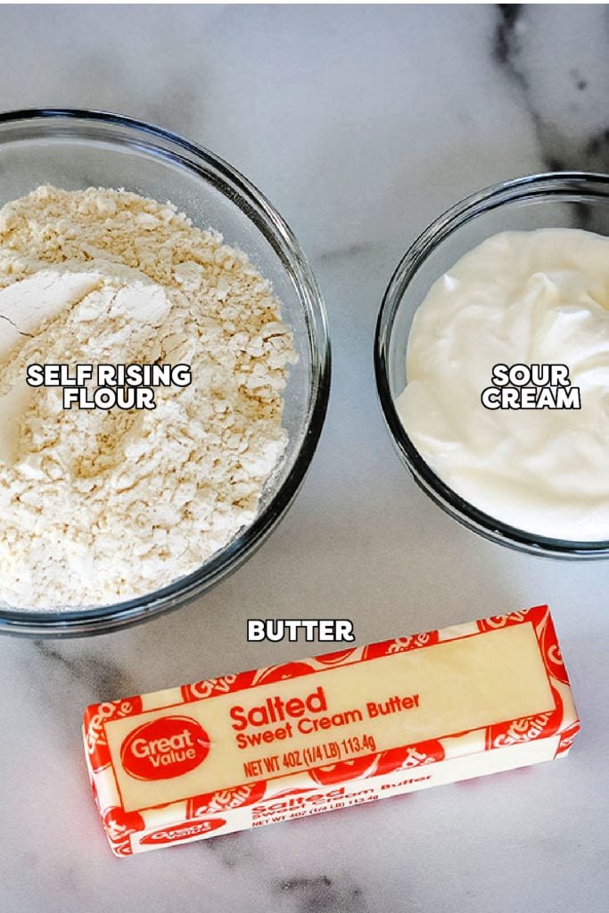 self rising flour, butter, and sour cream laid out to make biscuits.