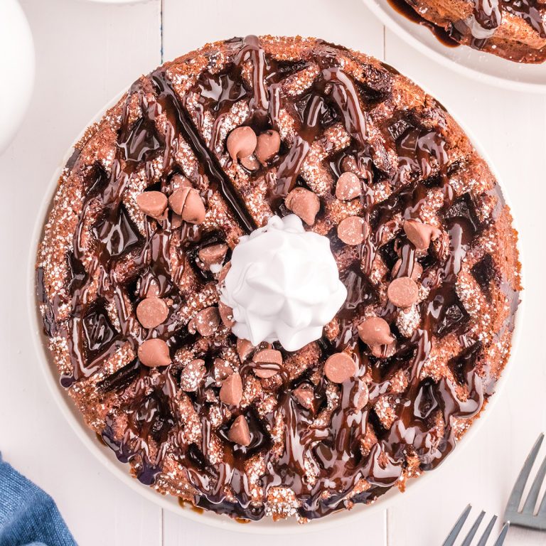 overhead shot of chocolate waffle with chocolate sauce, chocolate chips, and whipped cream.