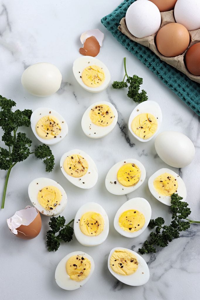 overhead shot of sliced hard boiled eggs on white marble.