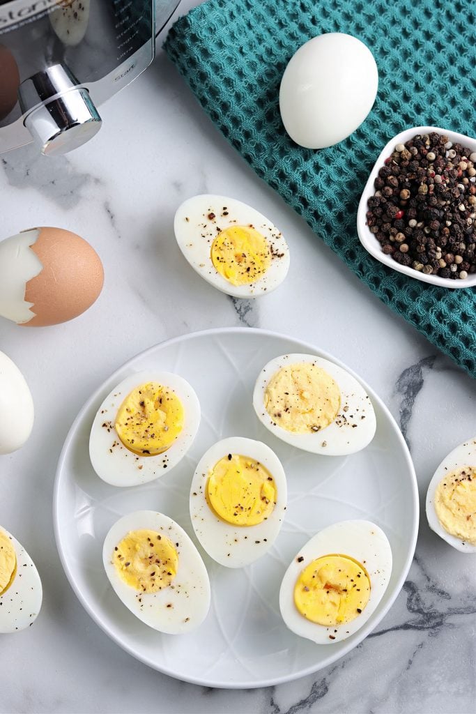 peppered hard boiled eggs on a white plate.