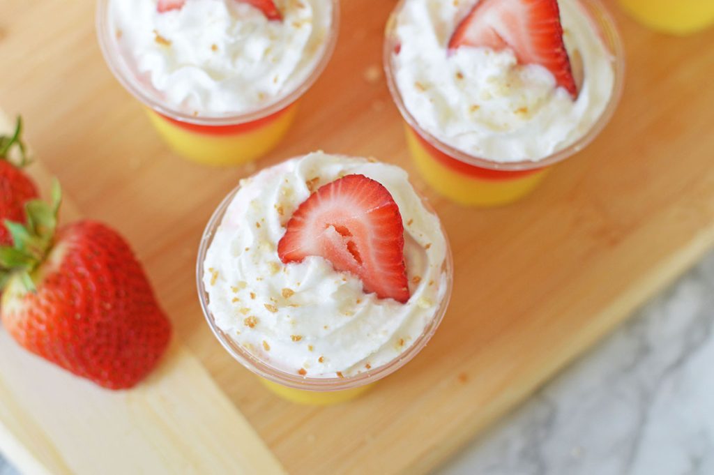 overhead shot of whipped cream & strawberry topped jello shot.