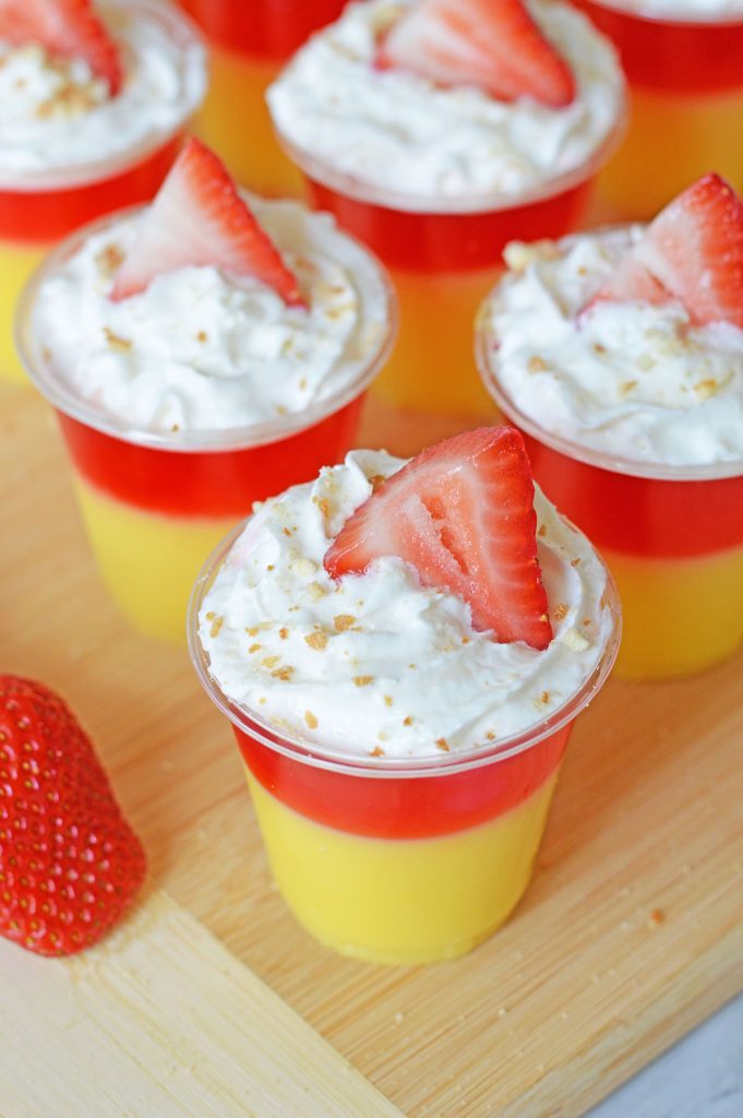strawberry shortcake jello shots on a wood board.