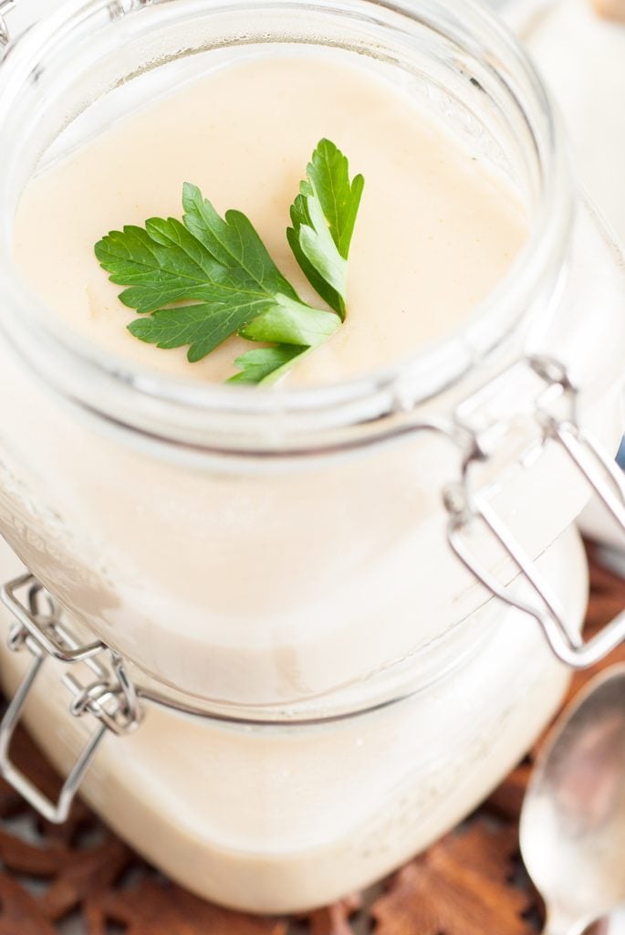 stack of two glass jars of homemade cream of chicken soup garnished with parsley. 