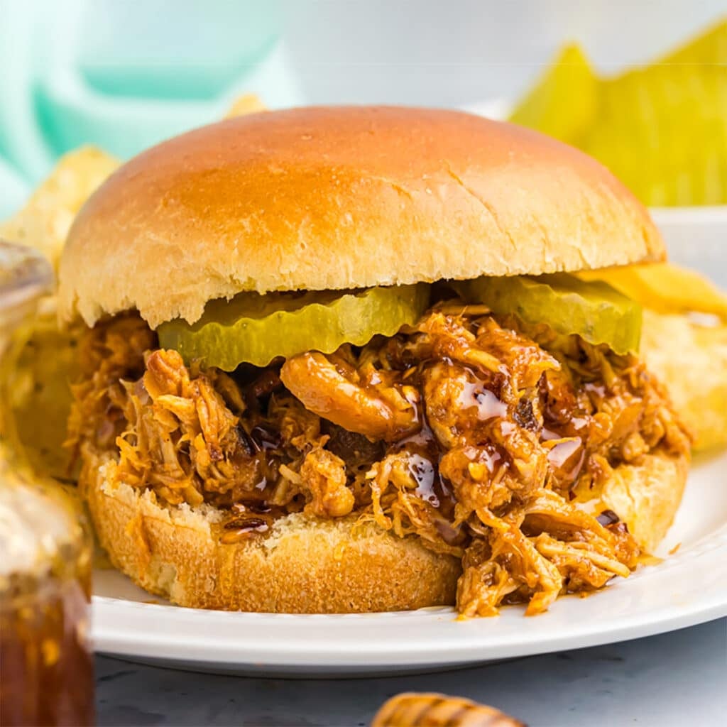 hot honey shredded chicken sandwich on a brioche bun topped with pickles.