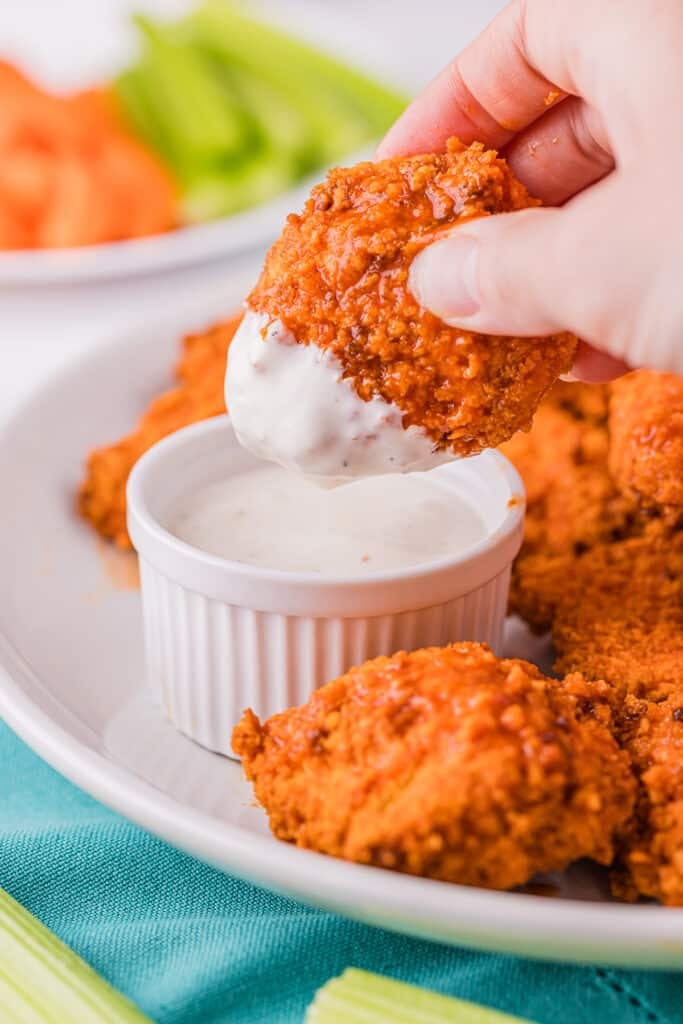 hand dipping a boneless wing into ranch dressing.