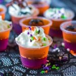 purple and orange jello shot topped with whipped cream & halloween sprinkles.