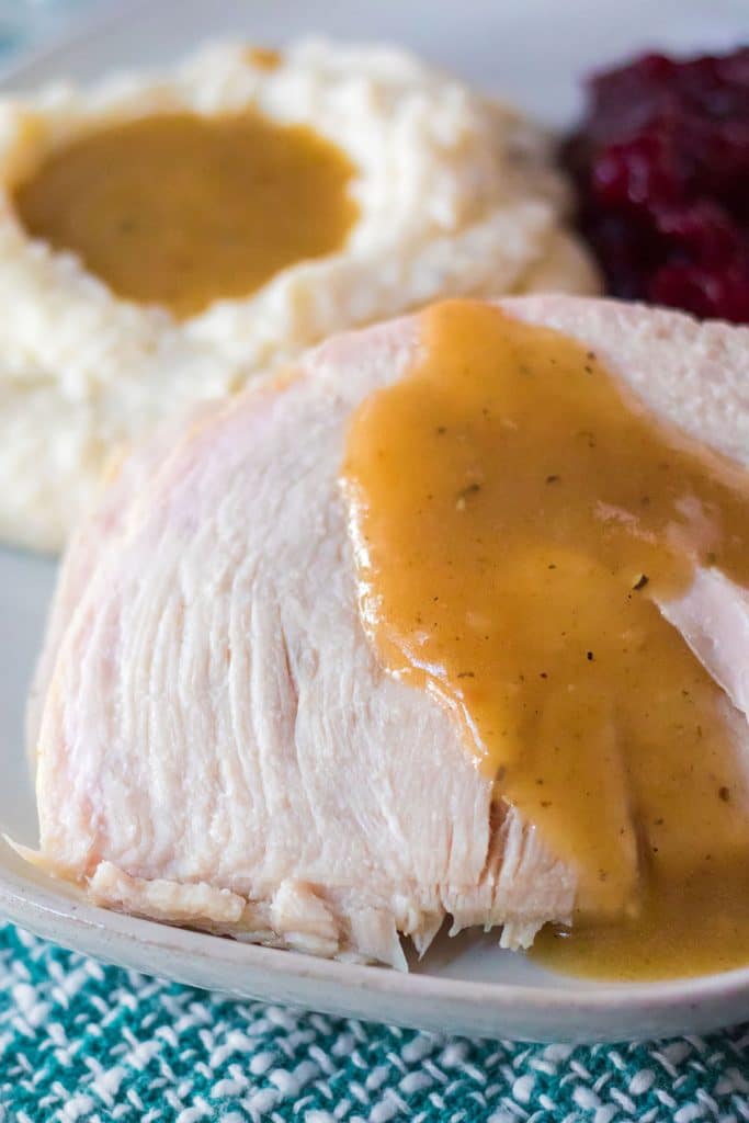 closeup of a slice of turkey breast topped with gravy.