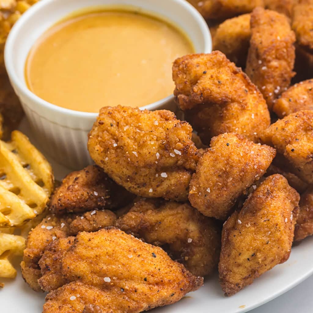 plate of copycat chick fil a chicken nuggets with a cup of sauce and waffle fries.