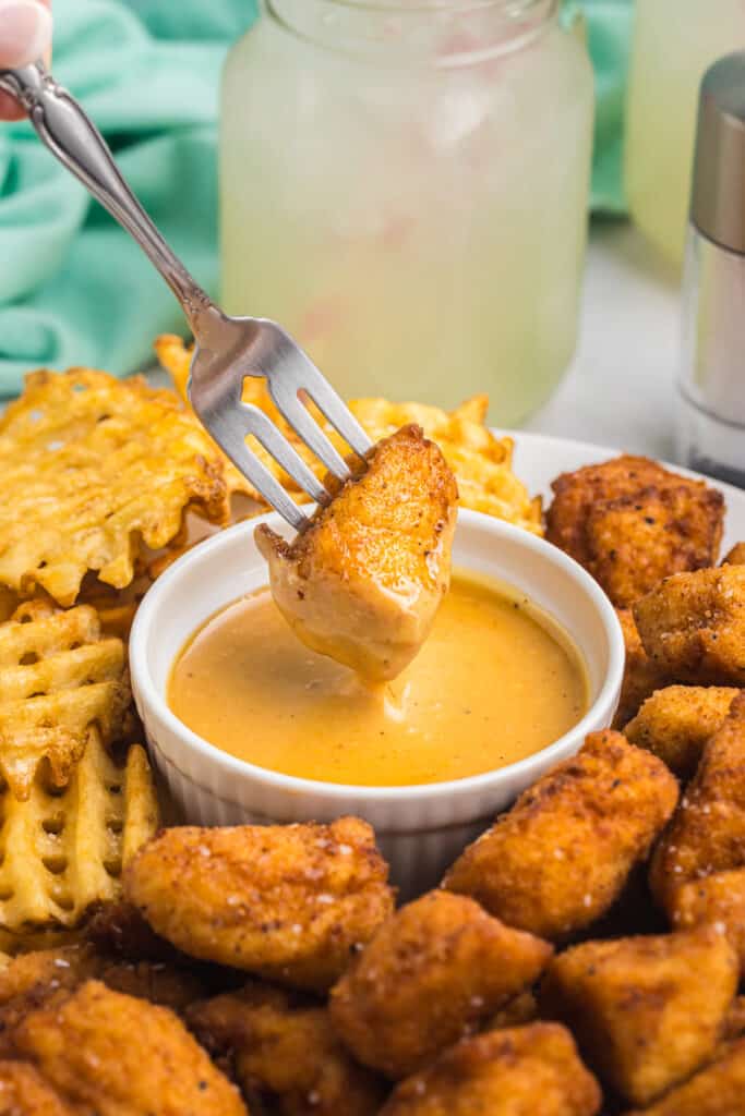 fork dipping a chicken nugget into chick-fil-a sauce.