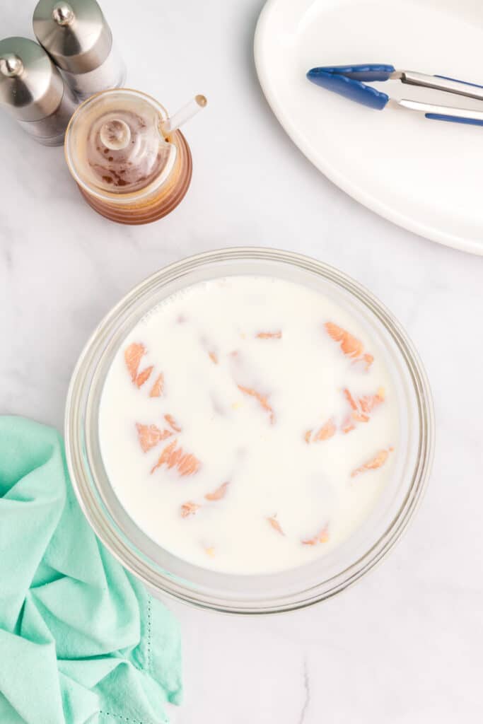 bowl of raw chicken marinating in a milky liquid.