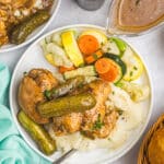 overhead shot of dill pickle chicken on a plate with mashed potatoes and vegetables.