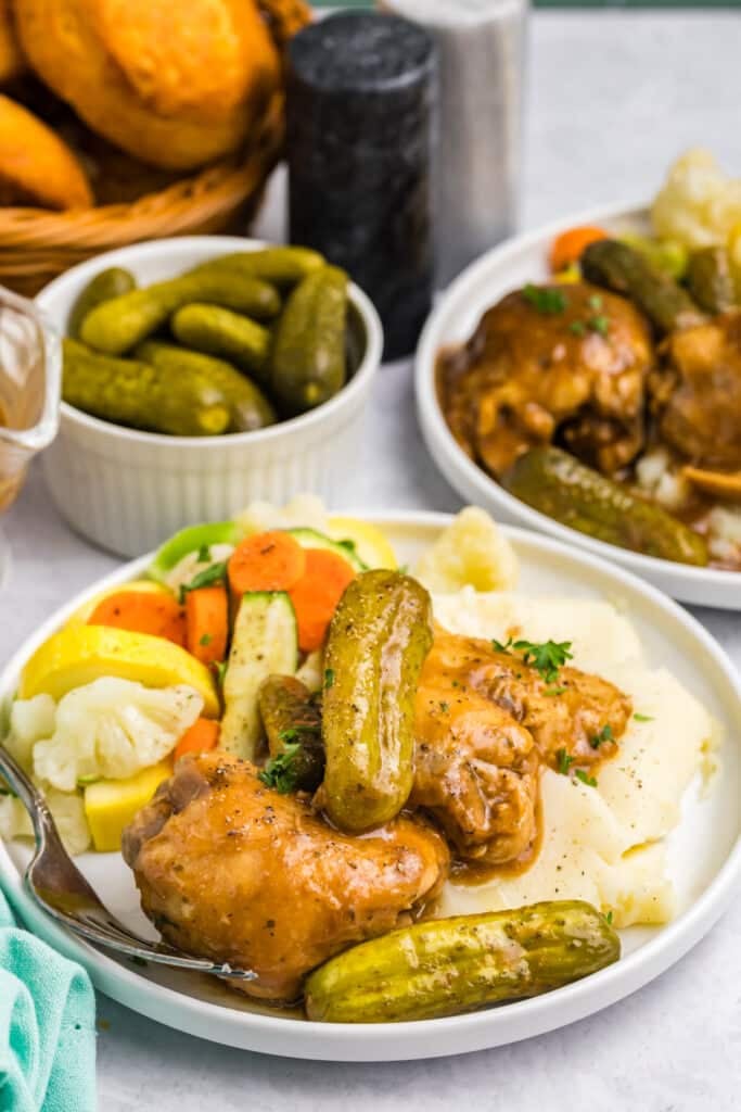 plate of pickle chicken with mashed potatoes and vegetables.