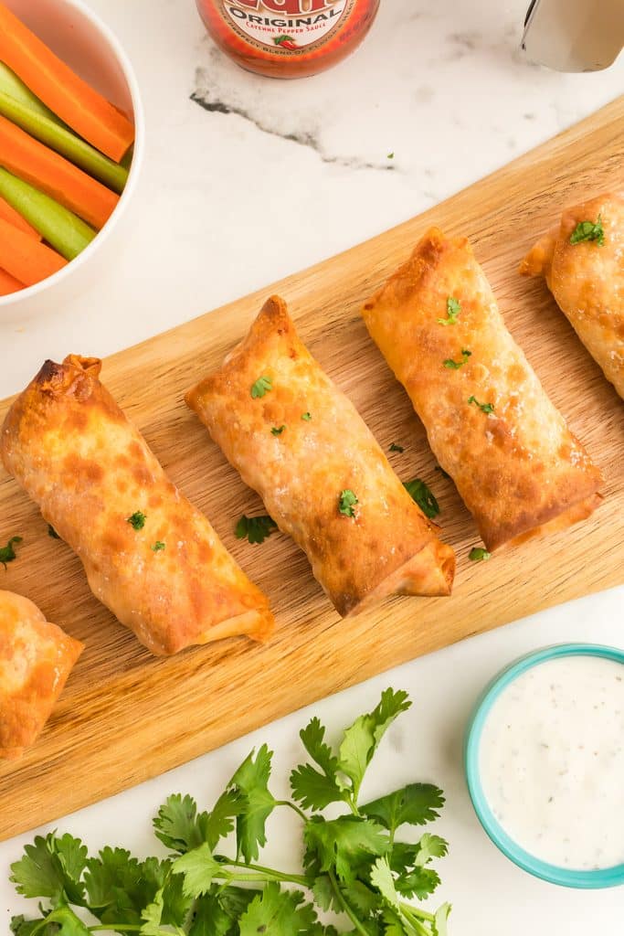 overhead shot of egg rolls on a wooden serving board.