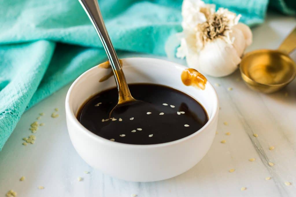 small white bowl of teriyaki sauce with a spoon in it.