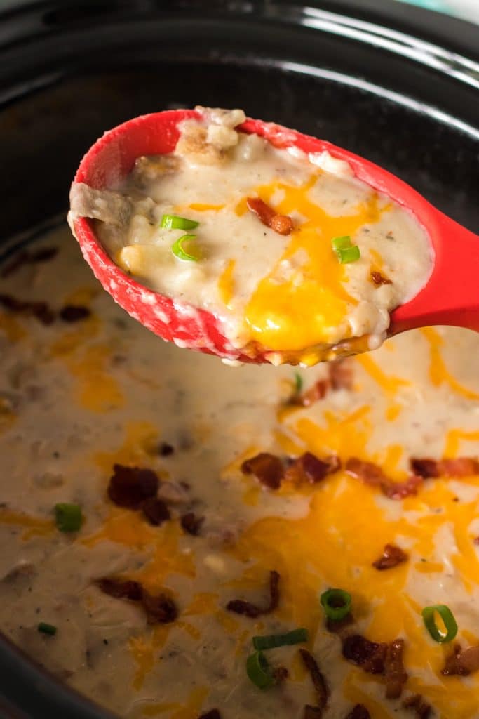 ladle lifting potato soup from a slow cooker.